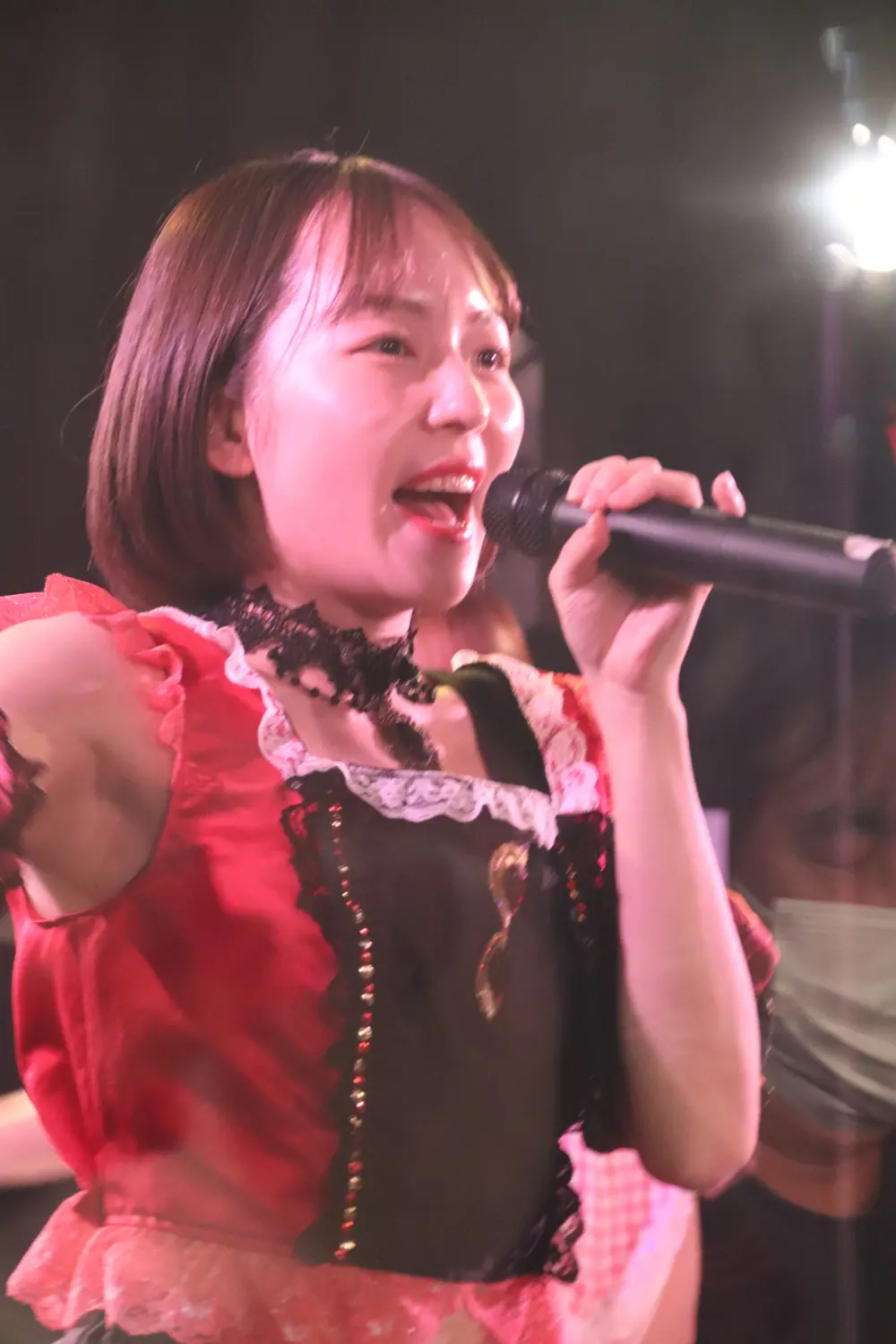 Nishimoto Meisa ถือไมโครโฟนร้องเพลงบนเวที