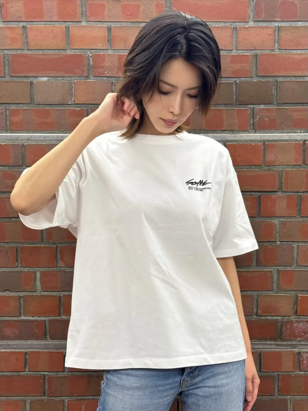 Mio Kimijima ในเสื้อยืดสีขาวหน้ากำแพงอิฐ