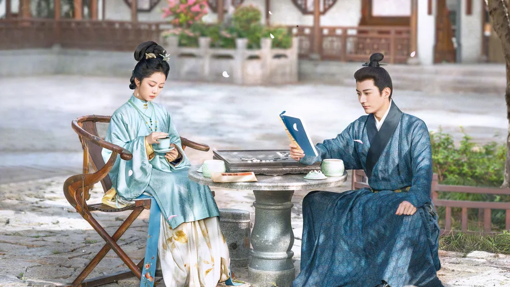 ฉากชายหญิงนั่งดื่มชาและอ่านหนังสือข้างโต๊ะหินในลานบ้านสไตล์โบราณ