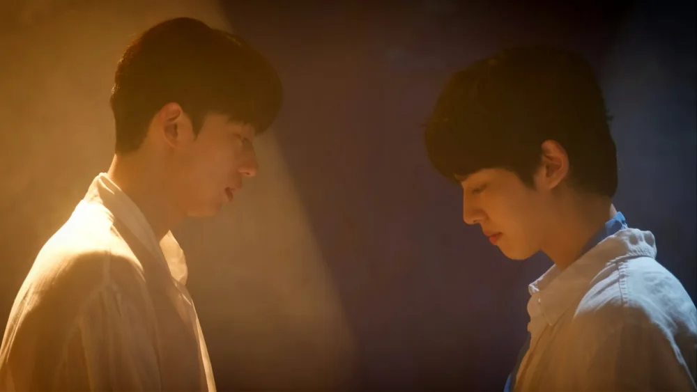 ชายสองคนยืนหันหน้าเข้าหากันในแสงไฟโทนอุ่น
